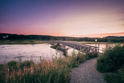 Bridge over river against sky during sunset