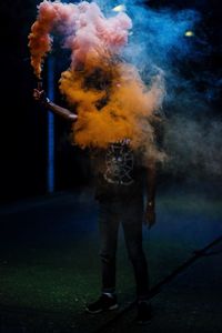 Close-up of man with arms outstretched at night