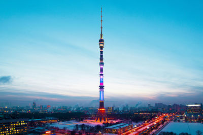 Communications tower in city against sky at dusk