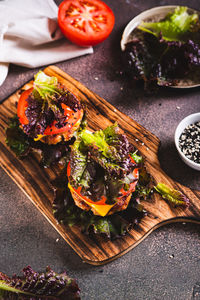 Juicy keto burgers on fresh lettuce leaves of cutlet, tomato and cheese on a board vertical view