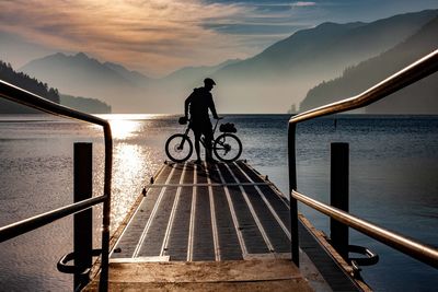 Man riding bicycle by sea against sky