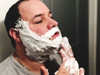 Close-up of man applying shaving cream on his face at bathroom