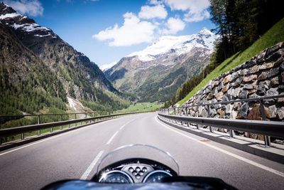 Road amidst mountains seen through car windshield