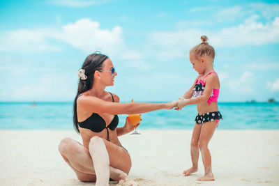 Rear view of mother and daughter on beach