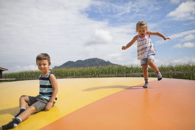 Brother and sister enjoying time outdoors, jumping on trampoline.