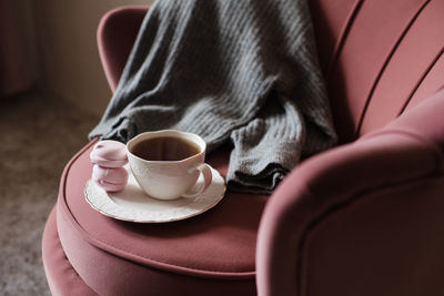 Cup of tea with knitted sweater stay in accent chair in room closeup. good morning. breakfast.