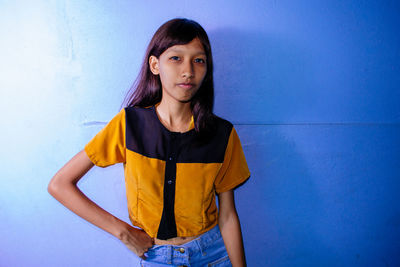 Young woman standing against wall