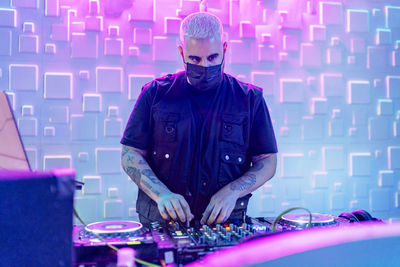 Man with umbrella standing in illuminated nightclub