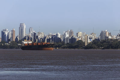 Sea by buildings against clear sky