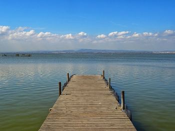 Wooden pier over lake against sky
