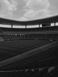 Empty seats in row against cloudy sky