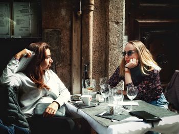 Friends sitting on chairs at sidewalk cafe