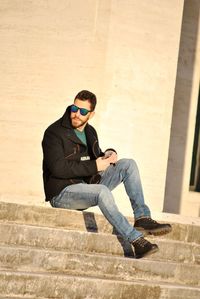 Full length of man sitting on staircase against wall