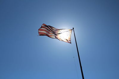 Low angle view of flag against clear blue sky