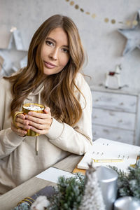 Young woman using mobile phone while sitting on table