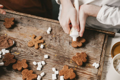 Children decorate the christmas gingerbread man with white frosting on a wooden background. 