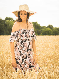 Beautiful woman wearing hat standing amidst crops on field