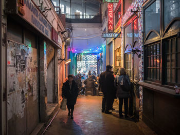 Rear view of people walking in alley