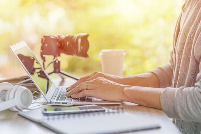 Midsection of woman using mobile phone on table