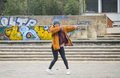 Full length of woman standing against graffiti in city