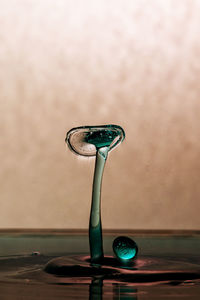 Close-up of water drops on glass table against wall