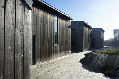 Wooden hut on footpath amidst buildings against sky