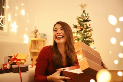 Portrait of smiling young woman holding christmas tree