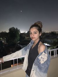 Portrait of beautiful young woman standing against sky