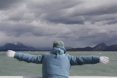 Rear view of man standing by mountain against sky