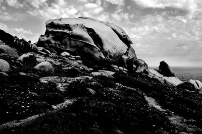 Rock formation on beach against sky