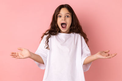 Portrait of young woman against pink background