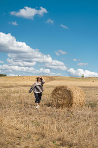 Woman with umbrella on field against sky