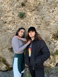 Portrait of smiling young women standing against rock formation