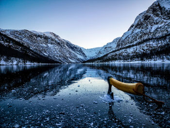 Scenic view of lake by snowcapped mountains against clear sky