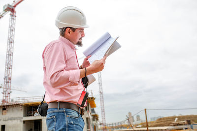 Man working on construction site against sky