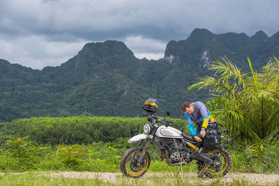 Man packing his scrambler type motorcycle in the mountains of thailand