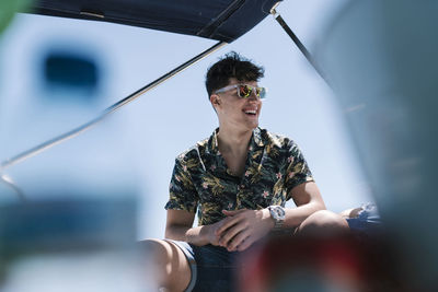 Young man laughing while sitting in yacht during sunny day