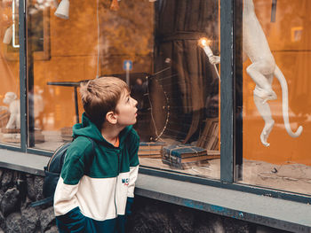 Boy looking through glass window