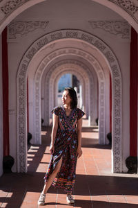 Asian female tourist in dress standing in arched passage of cikang overpass bridge and looking away during holiday in taiwan