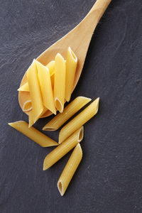 Close-up of penne in wooden spoon on slate