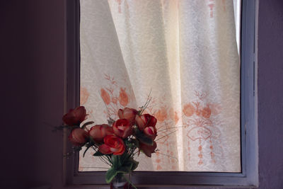 Close-up of rose against window at home