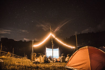 Illuminated tent on field against sky at night