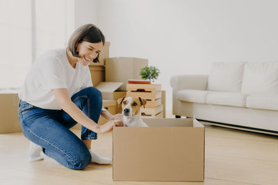 Full length of woman using phone while sitting on floor at home