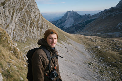 Portrait of young man standing on land against mountains and sky