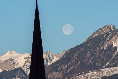 Schaan, liechtenstein, january 19, 2022 full moon in the morning behind a tower of a catholic church