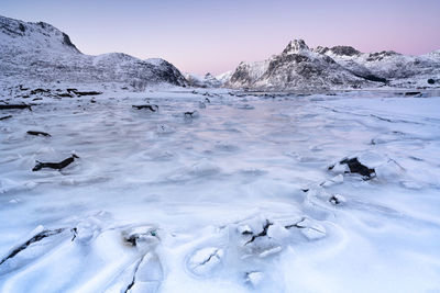 Scenic view of glacier and snowcapped mountains against sky