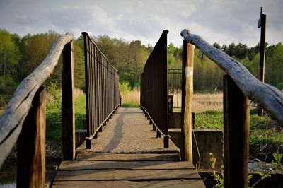 Footbridge amidst trees against sky