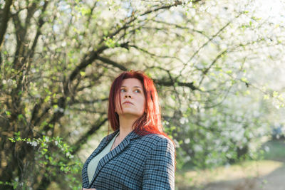 Portrait of young woman standing against trees