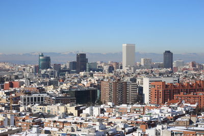 Aerial view of buildings in city against clear sky