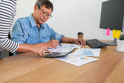 Midsection of man using mobile phone while sitting on table